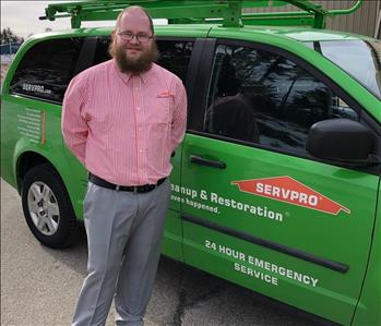 Male employee smiling in front of SERVPRO Van