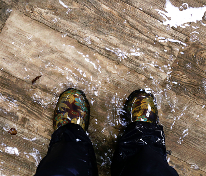 a person standing in water boots in a flooded room
