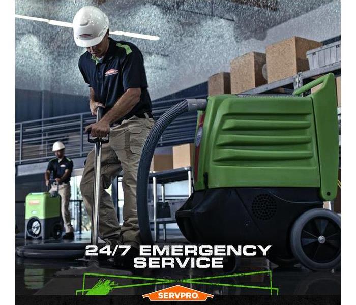 SERVPRO crew extracting water from a flooded building with the caption: "24/7 Emergency Service"