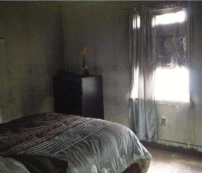 bedroom with walls and bed covered in soot damage